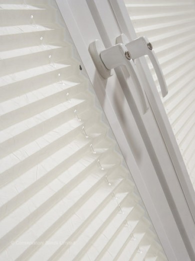 An image of a door handle with perfect fit pleated blinds to its side