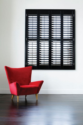 A picture of a room with a red chair and black plantation shutters Cardiff